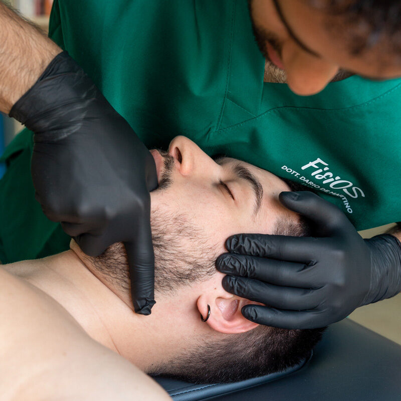 Dottore Dario De Martino effettua una manipolazione per la riabilitazione dell'articolazione temporo-mandibolare su paziente uomo durante un trattamento osteopatico e fisioterapico per la cura del dolore alla cervicale e del mal di testa