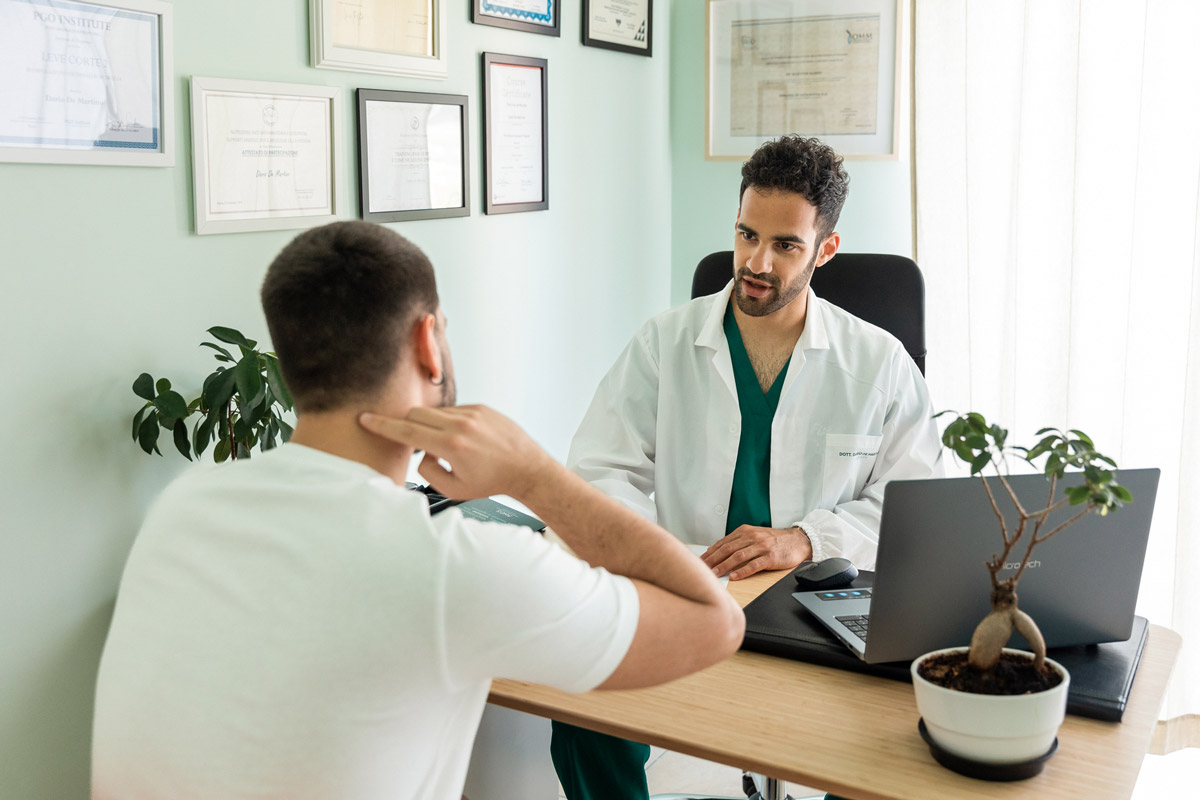 Paziente uomo che mostra al medico il punto in cui sente dolore al collo per il trattamento della cervicalgia