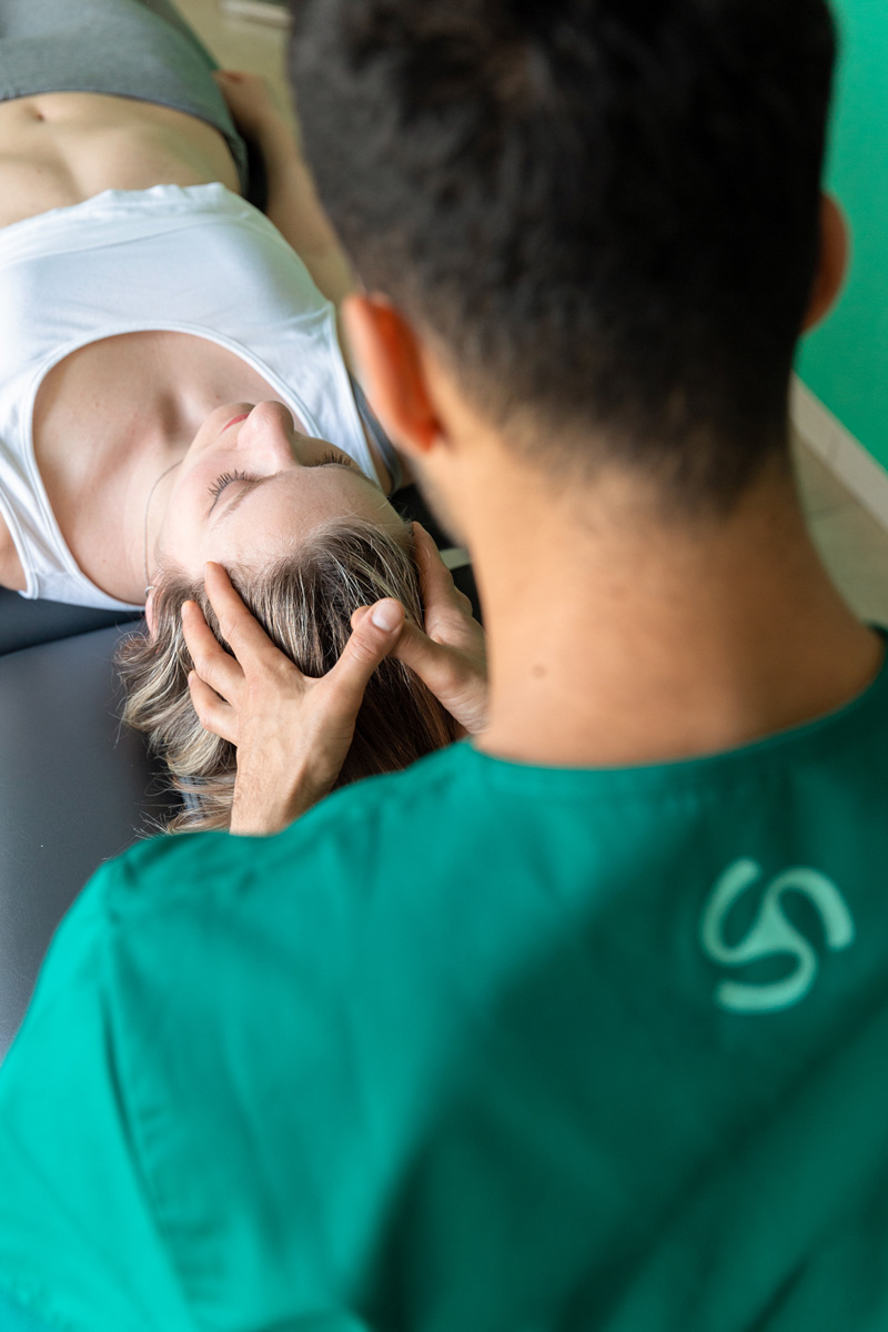 Dottore Dario De Martino effettua una manipolazione cranio-sacrale a una paziente donna durante un trattamento osteopatico per la cura del mal di testa