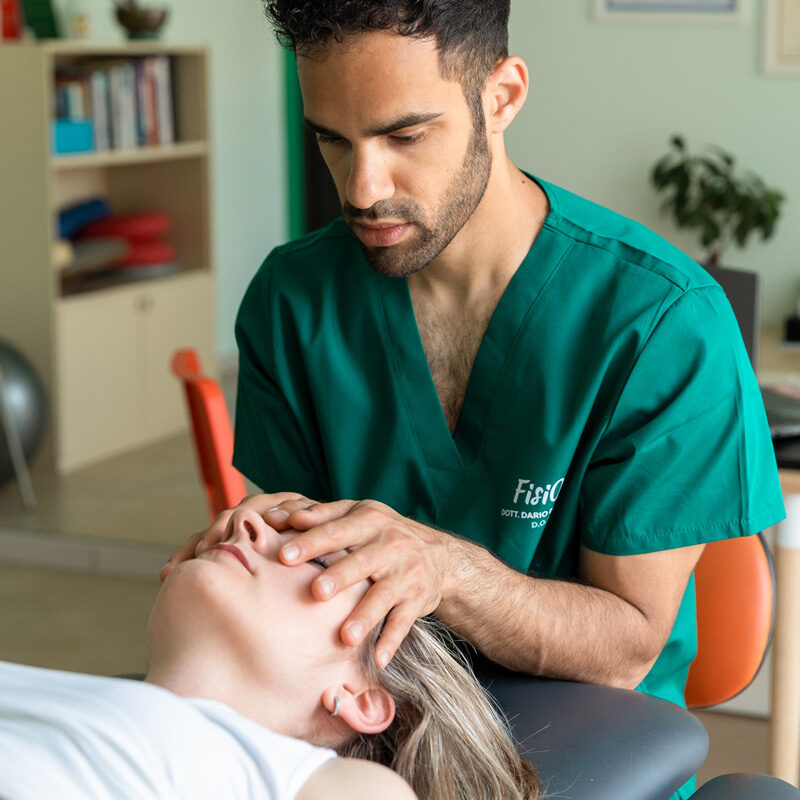 Dottore Dario De Martino effettua una manipolazione cranio-sacrale a una paziente donna durante un trattamento osteopatico per la cura del mal di testa