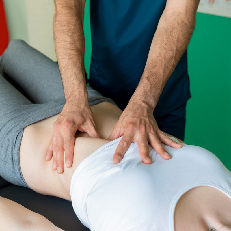 Dottore Dario De Martino effettua una manipolazione all'addome durante un trattamento di osteopatia e fisioterapia su paziente donna