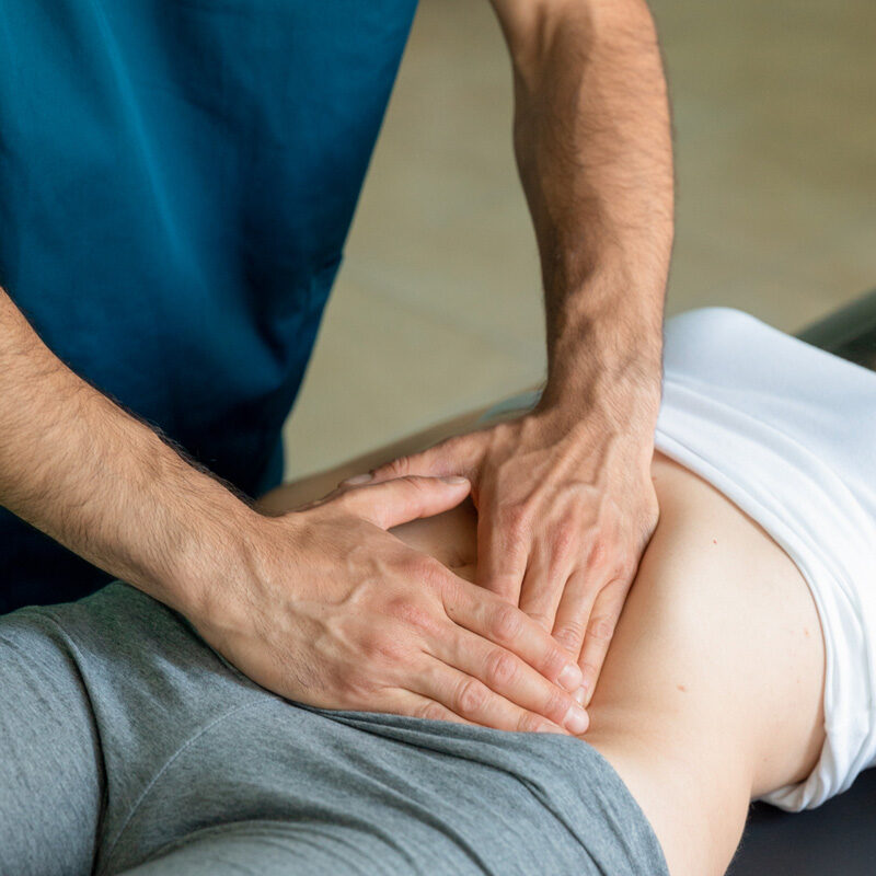 Dottore Dario De Martino effettua una manipolazione all'addome durante un trattamento di osteopatia e fisioterapia su paziente donna