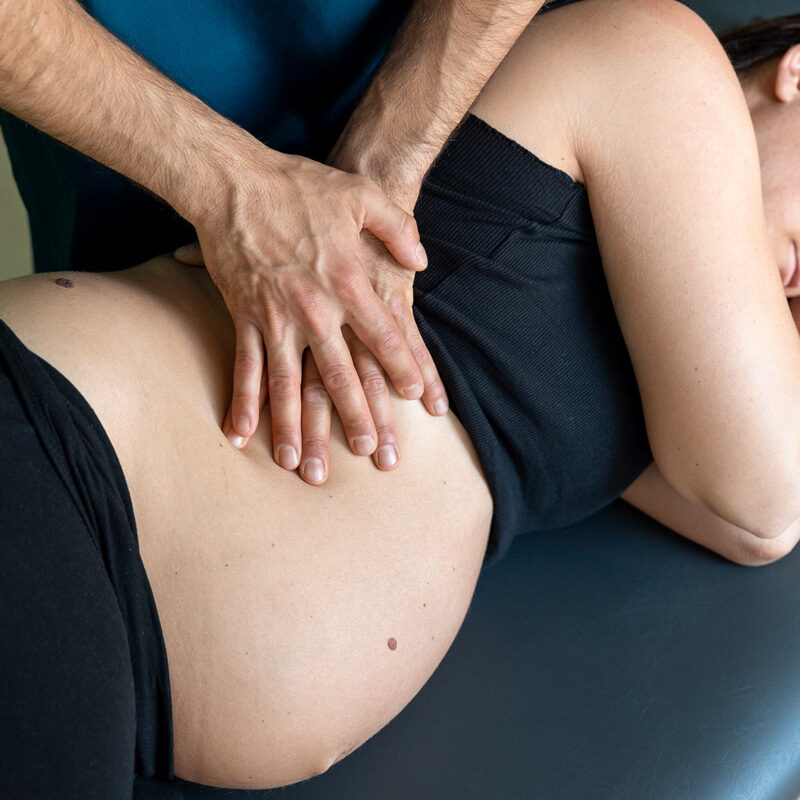 Dottore Dario De Martino durante un trattamento osteopatico per paziente donna in gravidanza. Dettaglio delle mani sul pancione