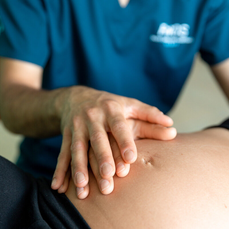 Dottore Dario De Martino durante un trattamento osteopatico per paziente donna in gravidanza. Dettaglio delle mani sul pancione